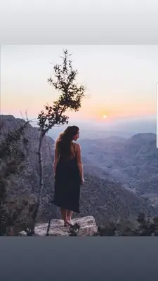 a woman standing on top of a mountain with the sunset at Dana Sunset Village Hotel in Dana