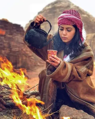 a woman is holding a pot over a fire at Dana Sunset Village Hotel in Dana
