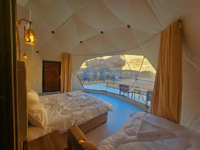 a bedroom with two beds and a large window at Hakon Matata Wadi Rum Jeep Tours Camp in Wadi Rum