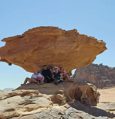 a group of people sitting on top of a rock at Hakon Matata Wadi Rum Jeep Tours Camp in Wadi Rum