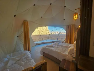 a bedroom with two beds and a large window at Hakon Matata Wadi Rum Jeep Tours Camp in Wadi Rum