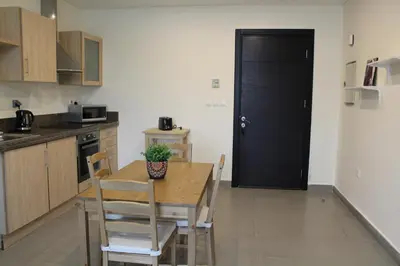 a kitchen with a table and chairs and a black door at Samarah Dead Sea Resort Apartment with Sea View FP4 Traveler Award 2025 Winner Thursday, Friday & Saturday Groups consisting solely of male guests are not permitted in Sowayma