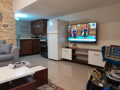 a living room with a television and a white refrigerator at MK2 - One Bedroom Apartment in Amman