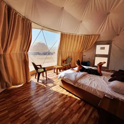 a person laying on a bed in a tent at Wadi Rum Calma camp in Aqaba