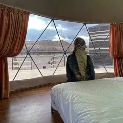 a person sitting next to a window looking out at the desert at Echo Desert Camp in Wadi Rum