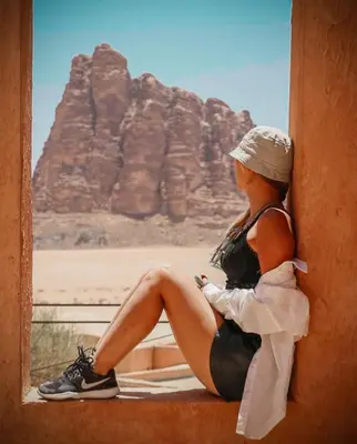 a woman sitting on a window sill looking at the desert at LARA lUXURY CAMP in Wadi Rum