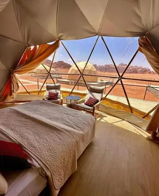 a bedroom with a bed and a view of the desert at LARA lUXURY CAMP in Wadi Rum