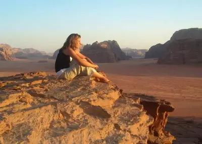 a woman sitting on a rock in the desert at Wadi Rum Majestic Camp in Wadi Rum