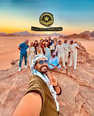 a group of people posing for a picture in the desert at RUM W BUBBLE lUXURY CAMP in Wadi Rum