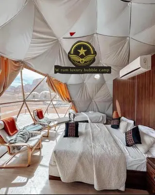 a bedroom with a bed and chairs in a tent at RUM W BUBBLE lUXURY CAMP in Wadi Rum