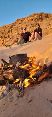 two people sitting around a fire on the beach at Panorama bubble camp in Disah
