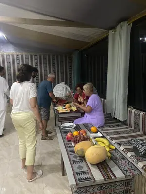 a group of people standing around a table with food at Red Twilight Camp in Disah