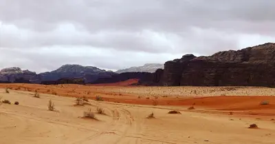 a desert scene with mountains and a dirt road at wadirumtours&camp in Wadi Rum