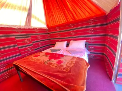 a bedroom with a bed in a red room at wadirumtours&camp in Wadi Rum