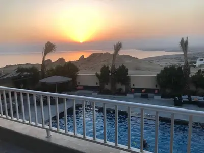 a sunset over a swimming pool in a resort at Taj Villa 1 deadsea - Entire Villa with sea view in Sowayma