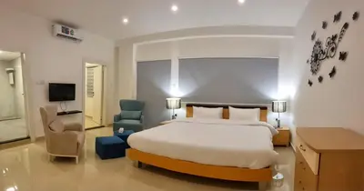 a bedroom with a bed and a chair and a television at Byblos Deluxe in Aqaba