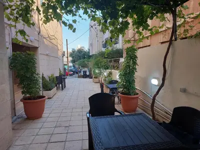 an empty sidewalk with chairs and tables and plants at Cozy Home 4 in Amman