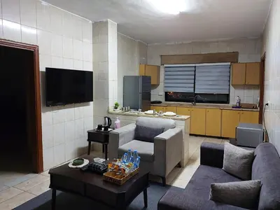 a living room with two couches and a kitchen at Cozy Home 4 in Amman