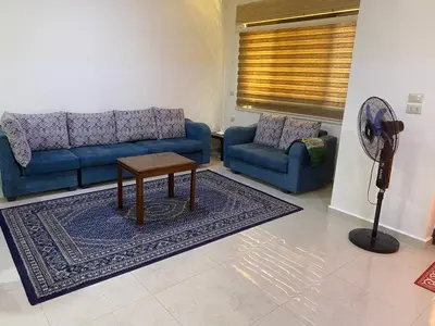 a living room with two blue couches and a table at Moon Apartments in Jerash