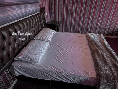 a bed with a brown headboard in a bedroom at wadi Rum bissan camp in Wadi Rum