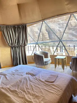 a bedroom with a bed and a large window at HILTON WADi RUM in Disah