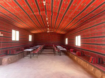 a room with red walls and tables and chairs at Desert Gate Camp in Wadi Rum