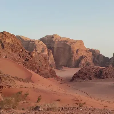 a desert with some rocks and some sand and bushes at camp scylla Wadi Rum in Wadi Rum