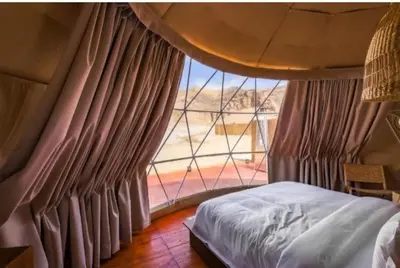 a bedroom with a bed and a large window at camp scylla Wadi Rum in Wadi Rum