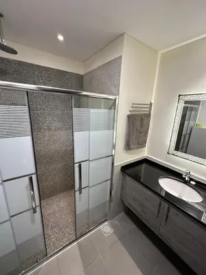 a bathroom with a glass shower and a sink at Dead Sea view Elite apartment Samara Resort traveler award 2024 in Sowayma