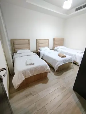 three beds in a room with wooden floors at Bridge apartments in Amman